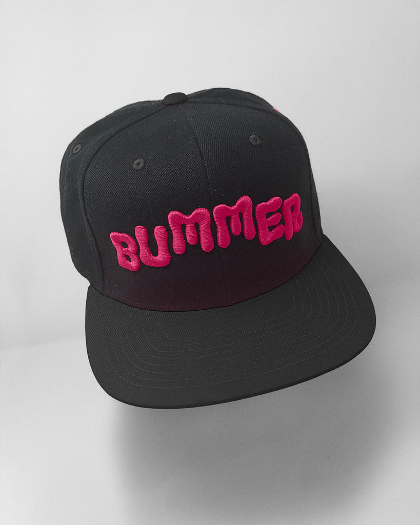 An all black hat with bummer on it in pink embroidery..