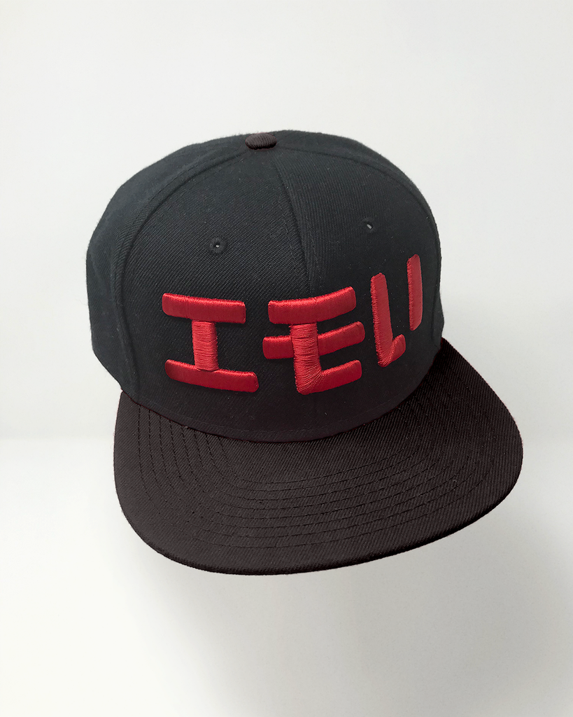A black hat with red embroidery of "エモい" on it