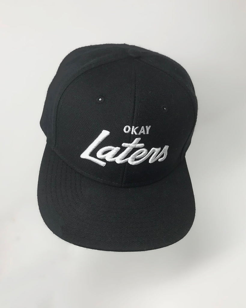 An all black hat with "okay laters" embroidered on it in white